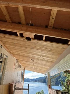 Partially installed cedar porch ceiling with exposed framing and light wiring