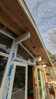 Cedar soffit boards above an exterior door and window during construction